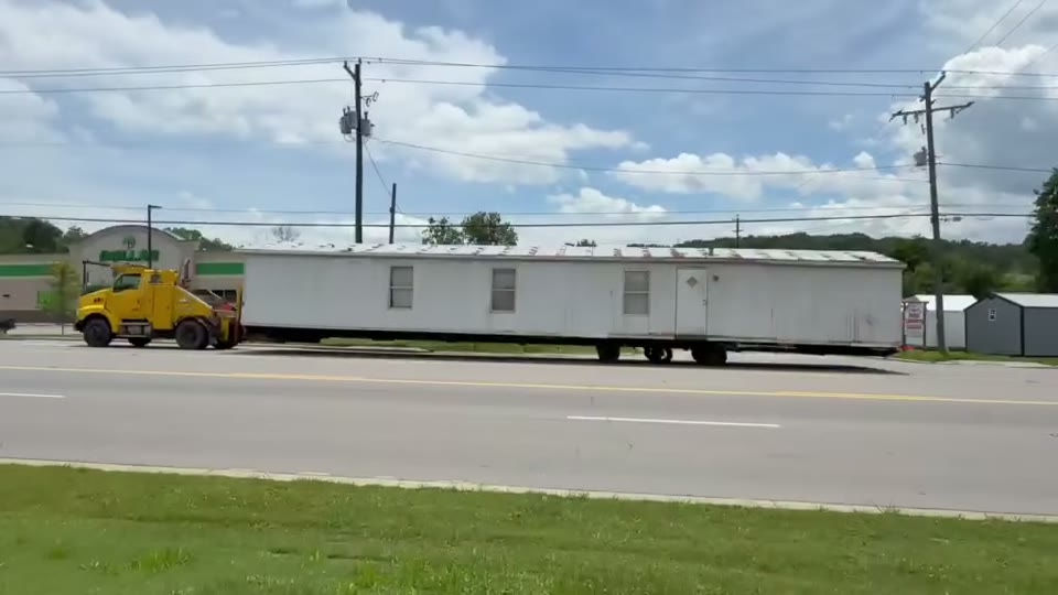 Our yellow truck pulling a white single-wide down the highway